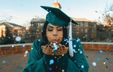 a graduate blowing confetti