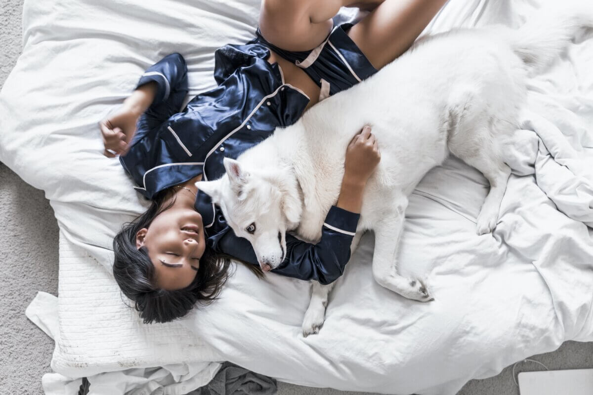 a woman in pajamas lays with her dog