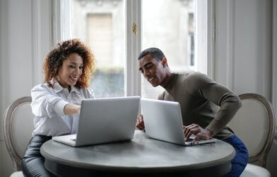 A man and woman working on their laptops at home