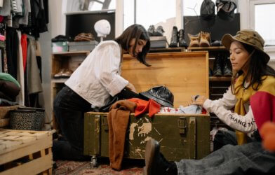 2 women look through a chest of used clothes