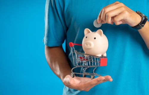 Man holding a piggy bank and a toy shopping cart