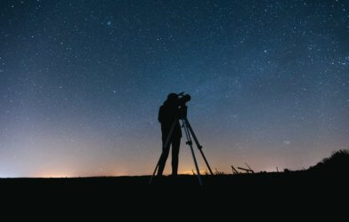 A person looking at the night sky using a telescope
