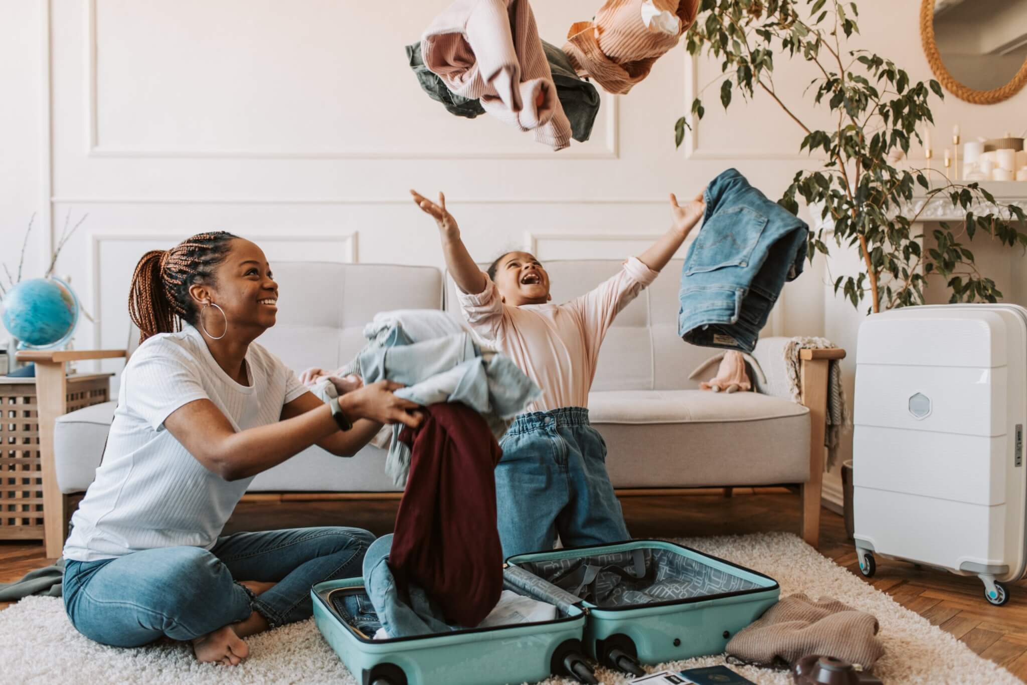 Child throwing clothes in the air while packing with mom