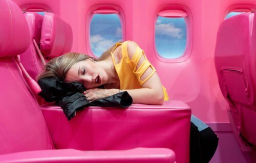 A woman sleeping on a plane using her jacket as a pillow