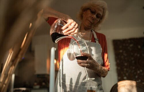 An Elderly Woman Pouring Wine into a Glass