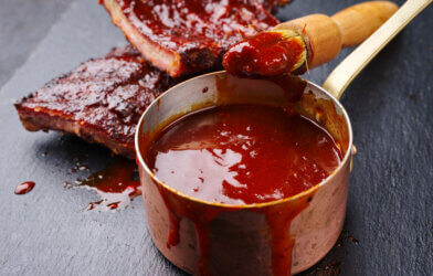 Hot and spicy barbecue sauce in a pot next to ribs