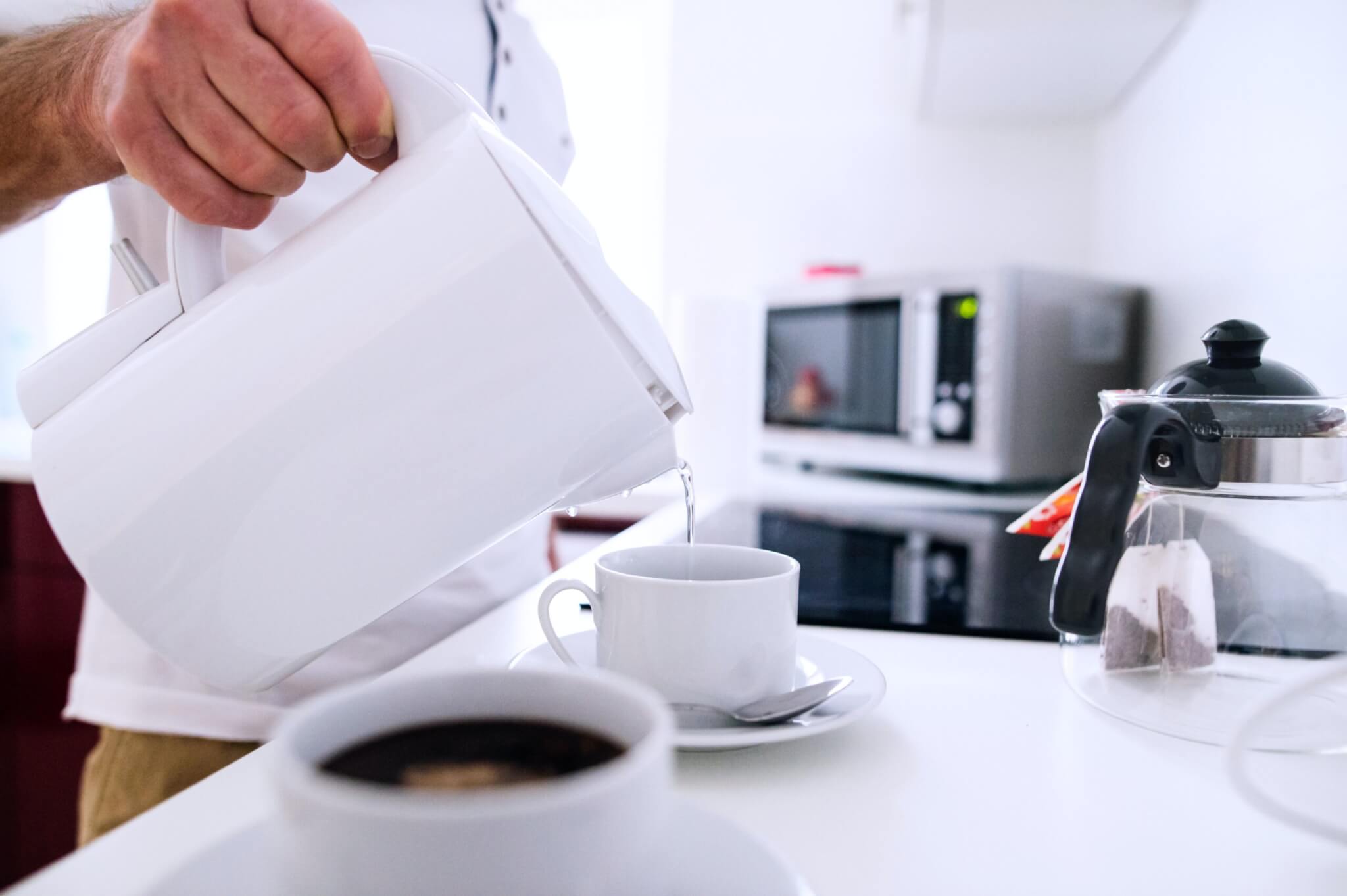 Person using electric kettle to pour tea