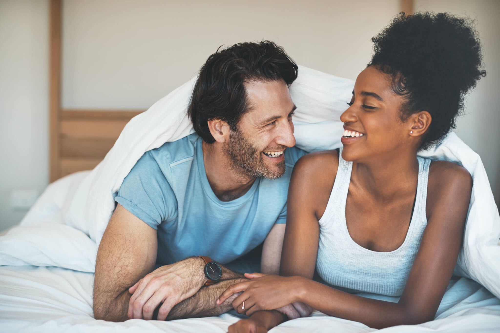 Happy couple in bed laughing