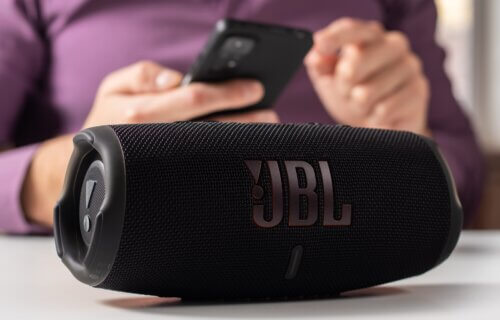 Person using JBL Charge 5 speaker with their smartphone