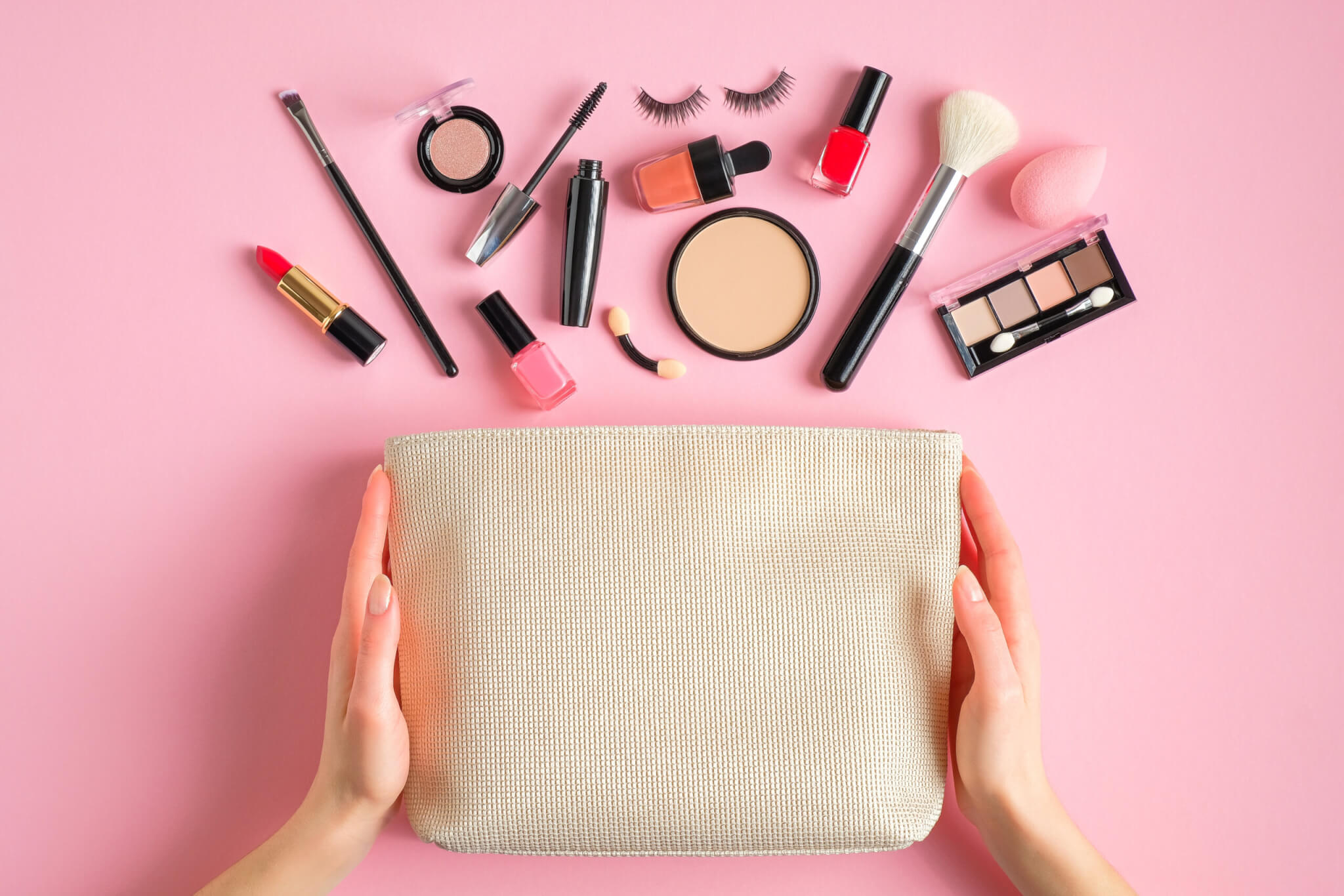 Female hands holding makeup bag with cosmetic beauty products