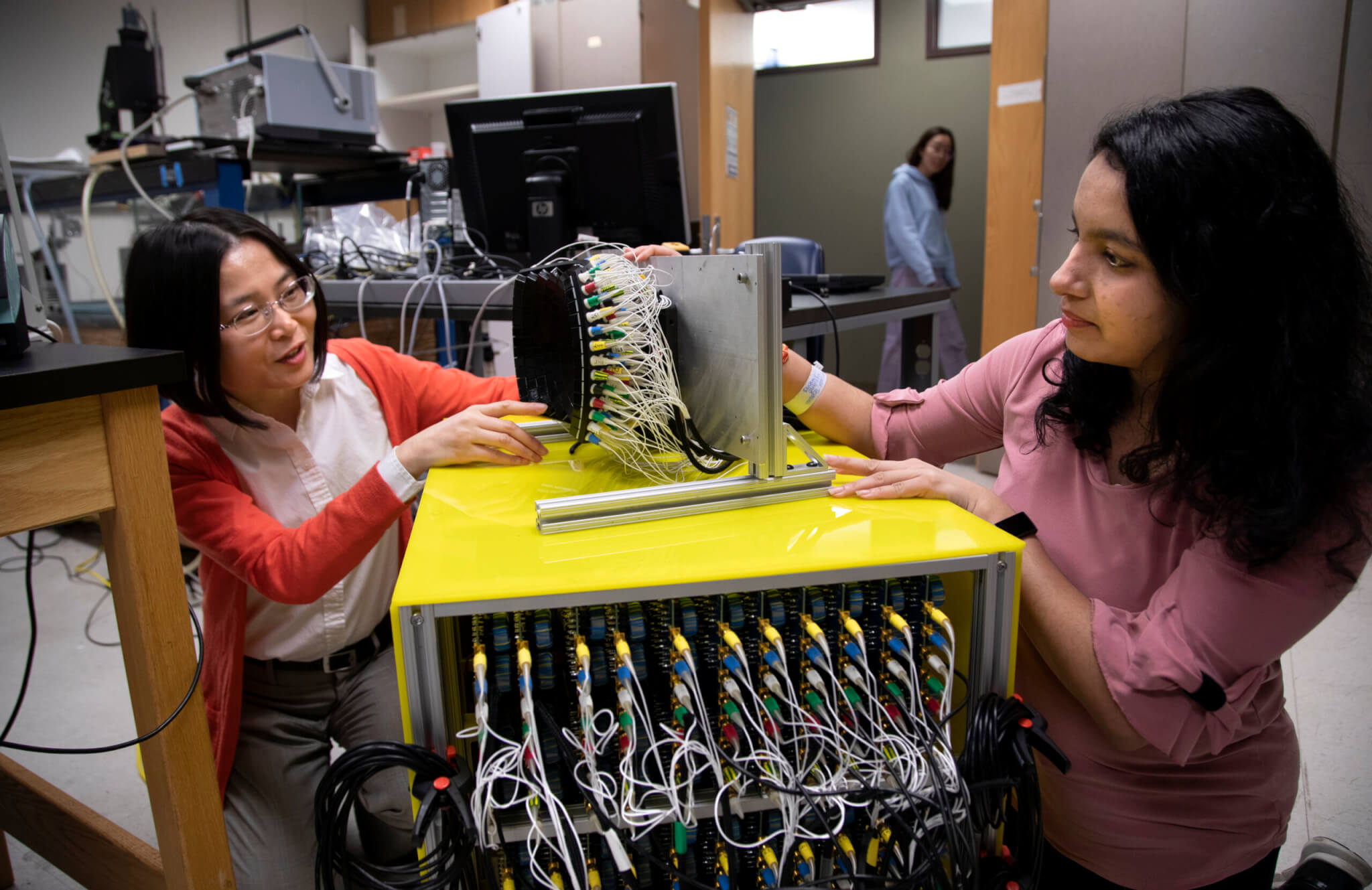 Zhen Xu, profesor de ingeniería biomédica en la Universidad de Michigan (izquierda) y Tejaswe Worlekar, estudiante de doctorado en ingeniería biomédica hablan sobre el transductor de ultrasonido de fragmentación de tejido de 700 kHz y 260 elementos que usan en el laboratorio del profesor Xu. 