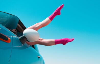 Woman wearing pink socks with feet out car window