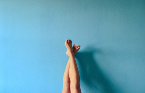a woman's legs up on a blue wall