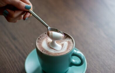 A spoon scoops up foam from a cup of coffee