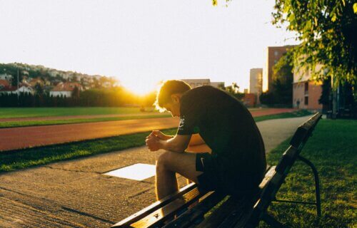 Male athlete sitting on a bench sad