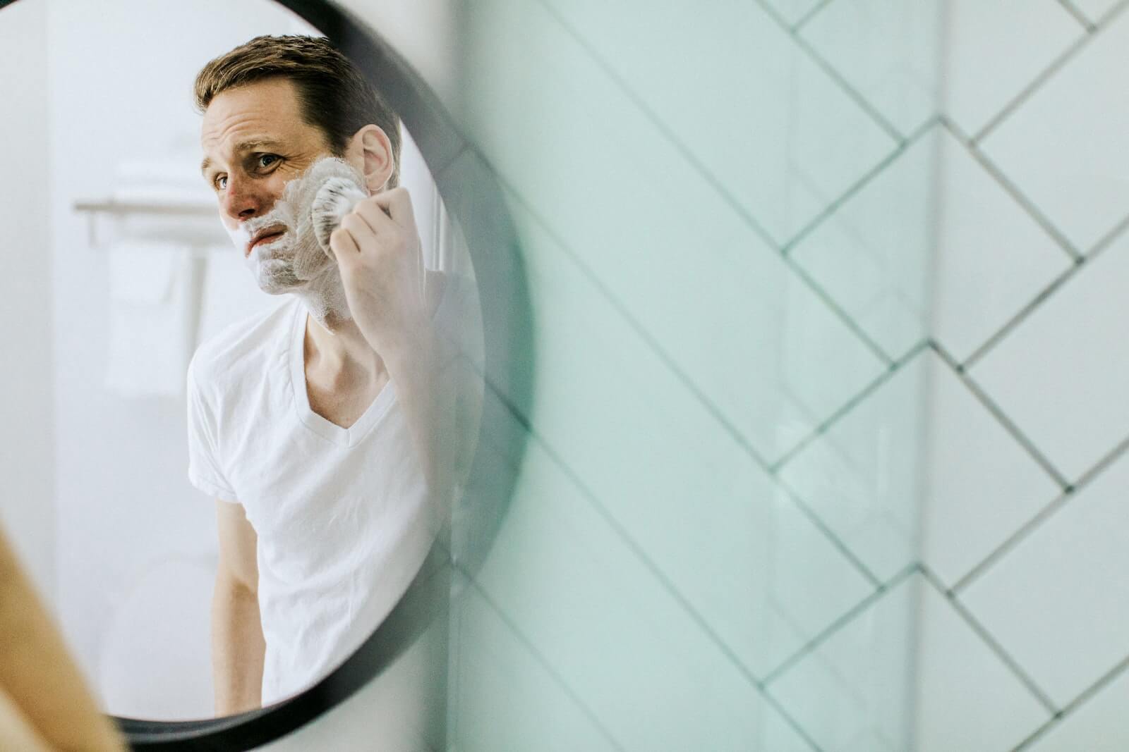Man applying shaving cream in front of mirror