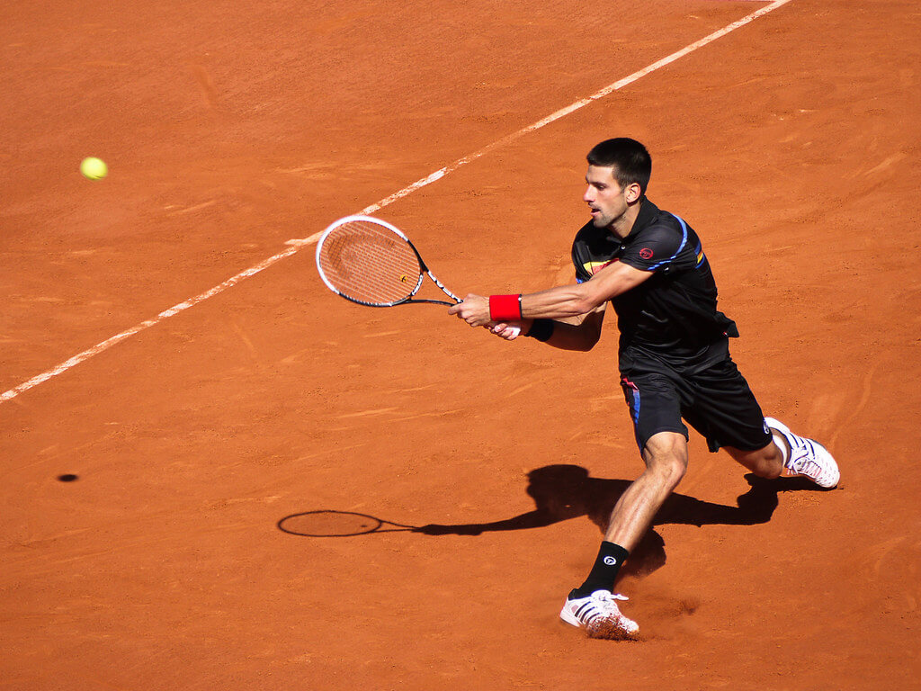 image of Novak Djokovic returning a serve in tennis match