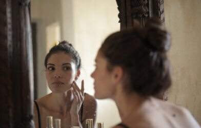 Woman doing skincare in front of mirror