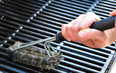 Person using a grill brush to clean their barbecue