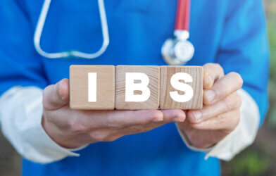 Physician holds three wooden blocks with IBS acronym for irritable bowel syndrome