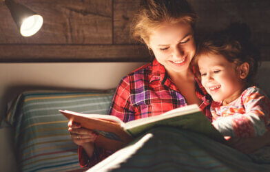 Mother reading to her young son in bed