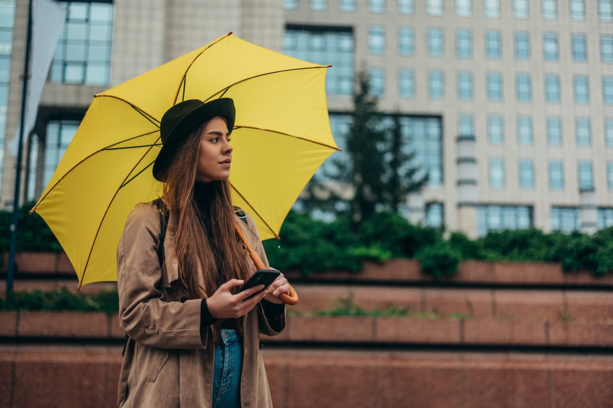 Woman looking at smartphone while holding umbrella