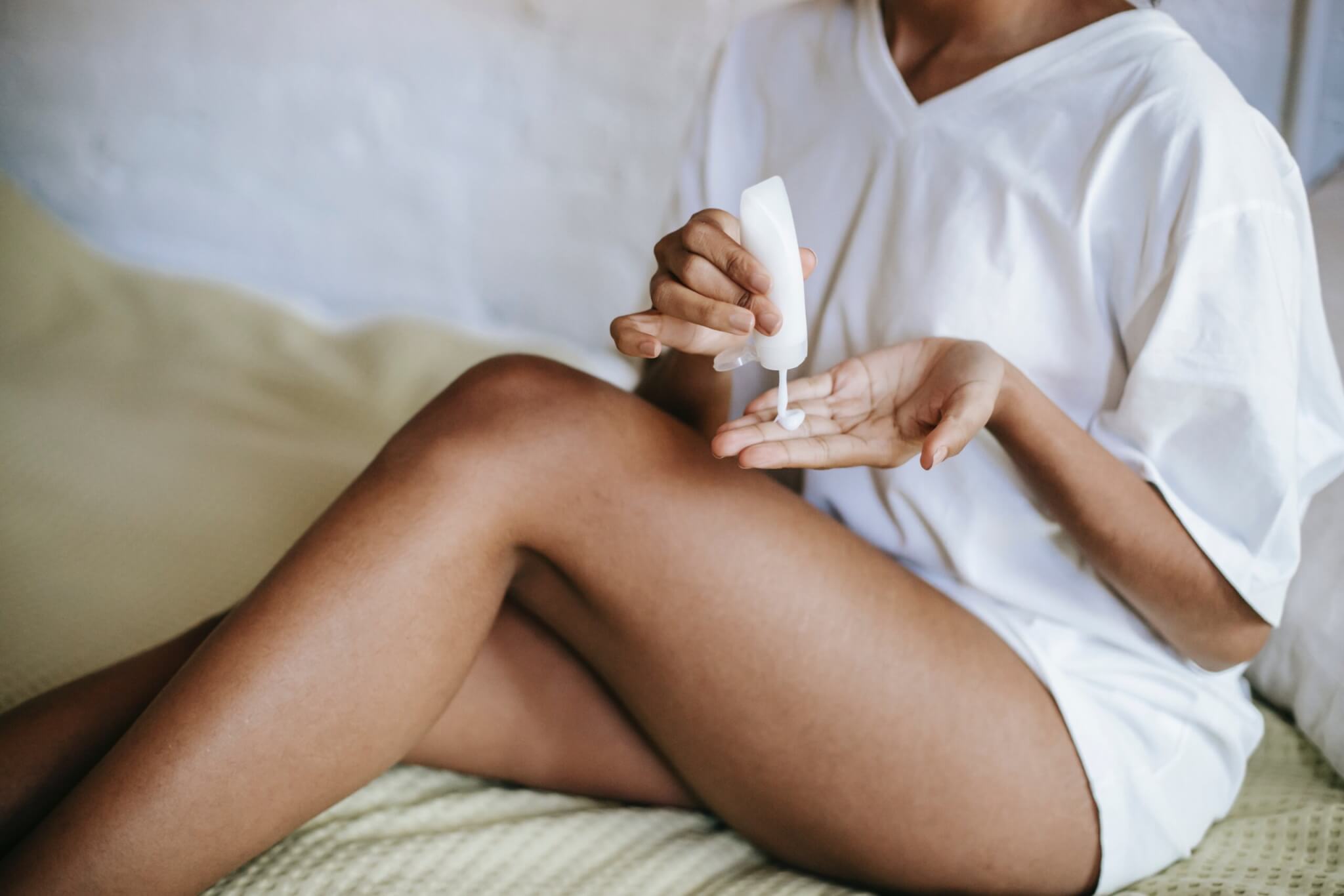 Woman rubbing body lotion on her legs