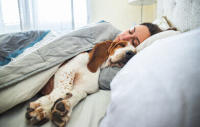Woman sleeping in bed with her dog
