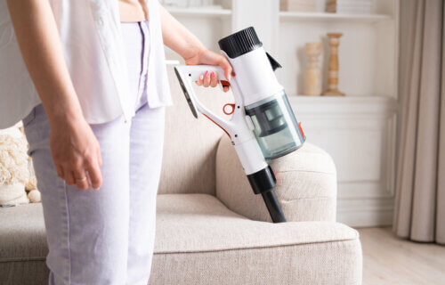 Woman using handheld vacuum on a couch