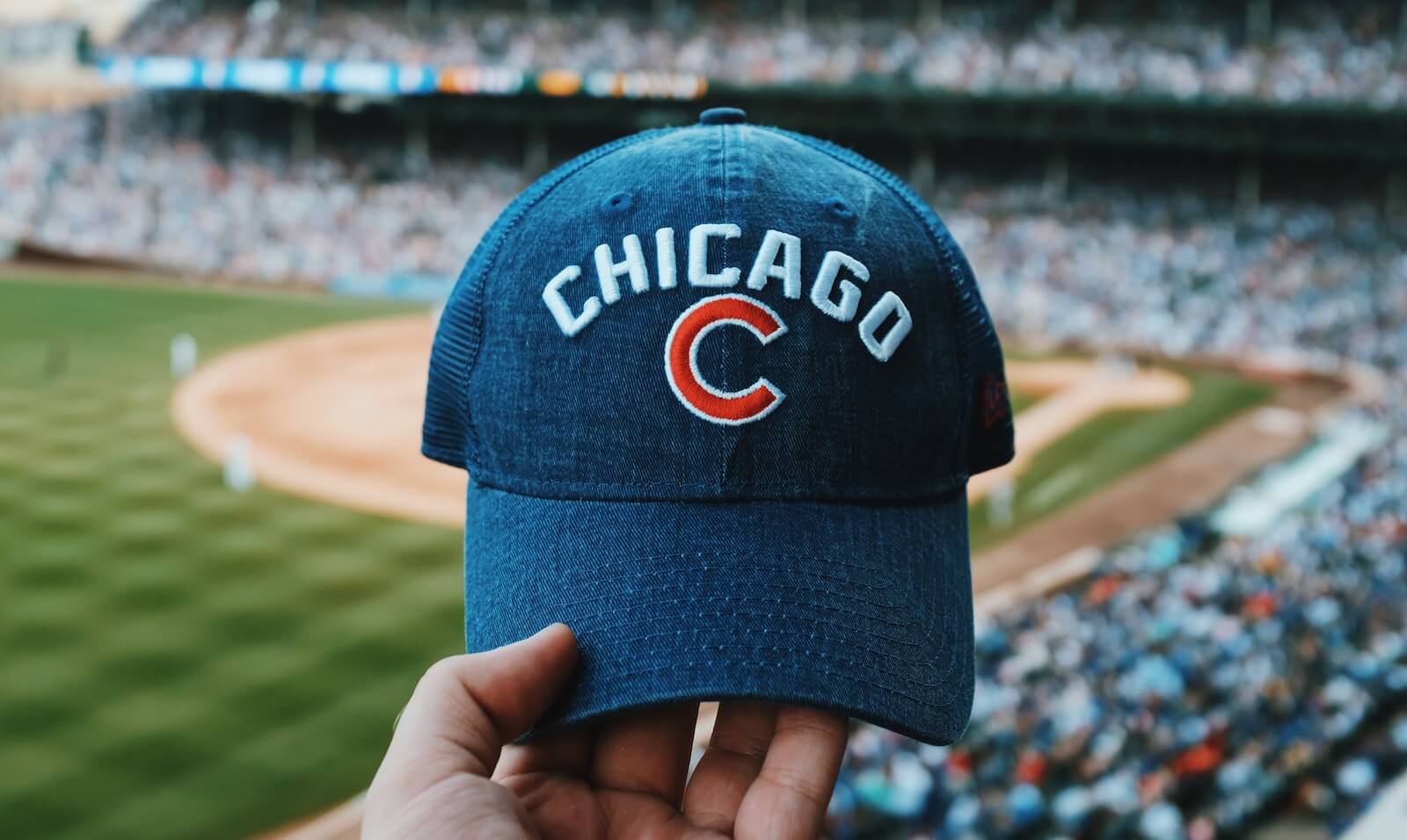 person holding blue Chicago Cubs cap at Wrigley field