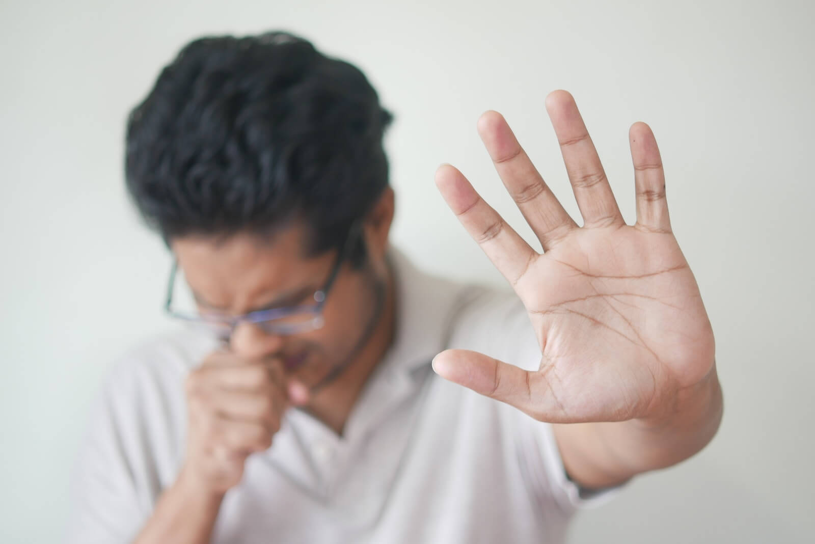 a man holding his hand up in front of his face to cough