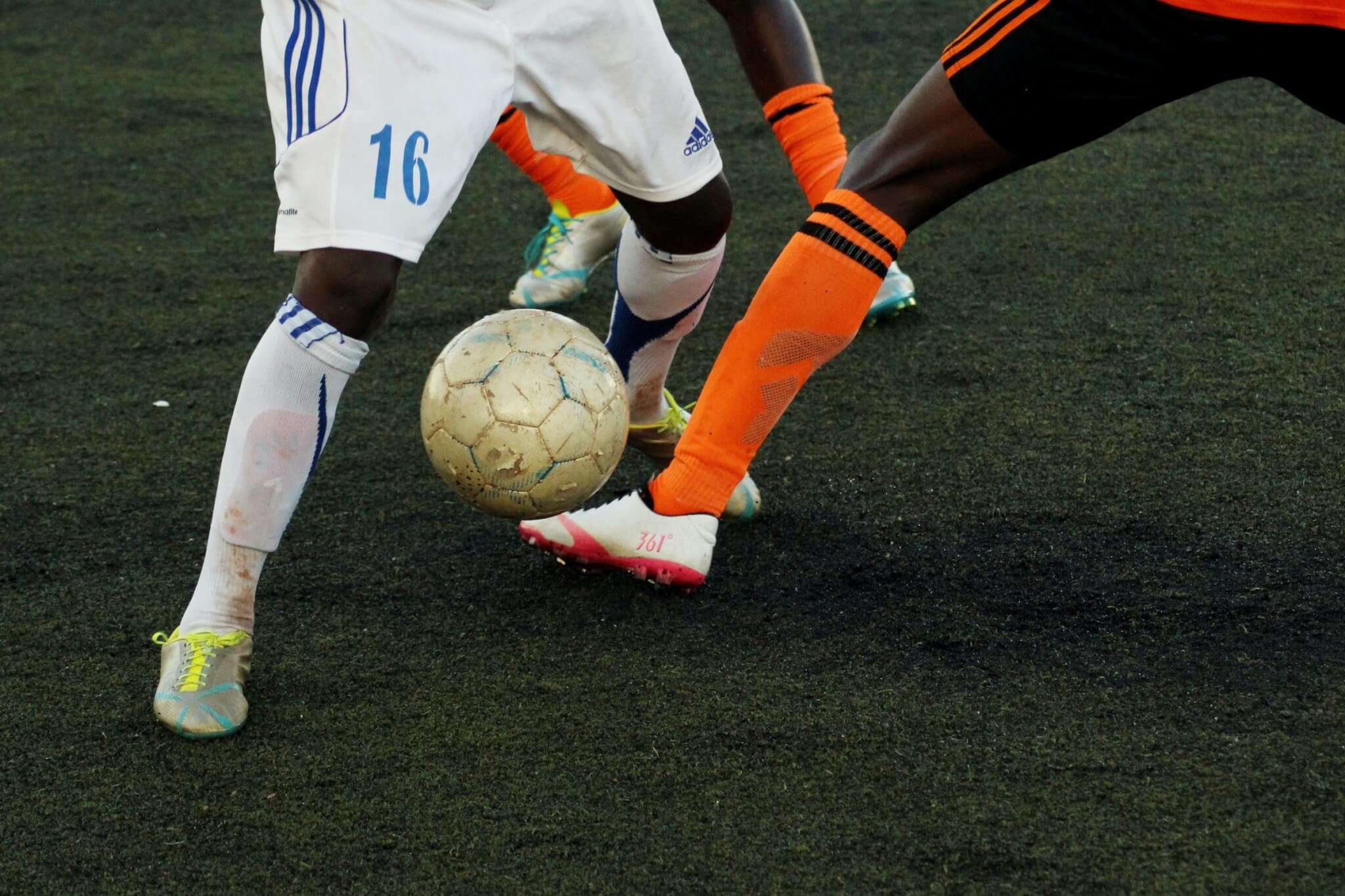 soccer players in white and orange dribbling a ball