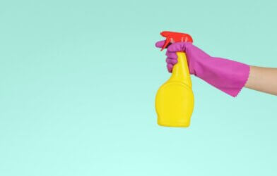 Person holding a bottle of cleaning spray