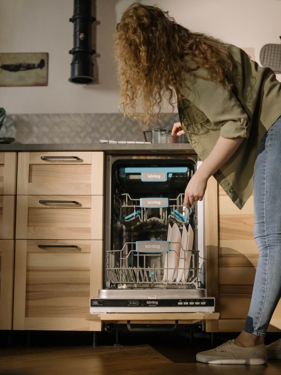Woman using Dishwasher in brown cabinetry
