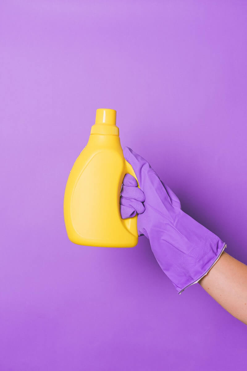 Person holding a yellow bottle of laundry detergent