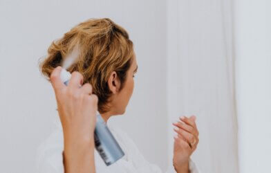 Woman applying dry shampoo to her hair