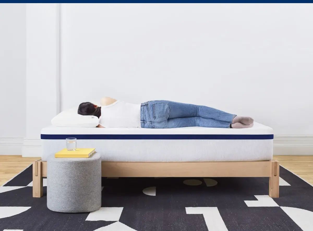 person in jeans sleeping on white and wood bed