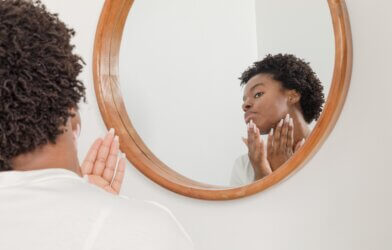 woman applying lotion in the mirror