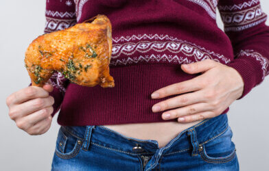 A woman holding her full stomach and a turkey leg