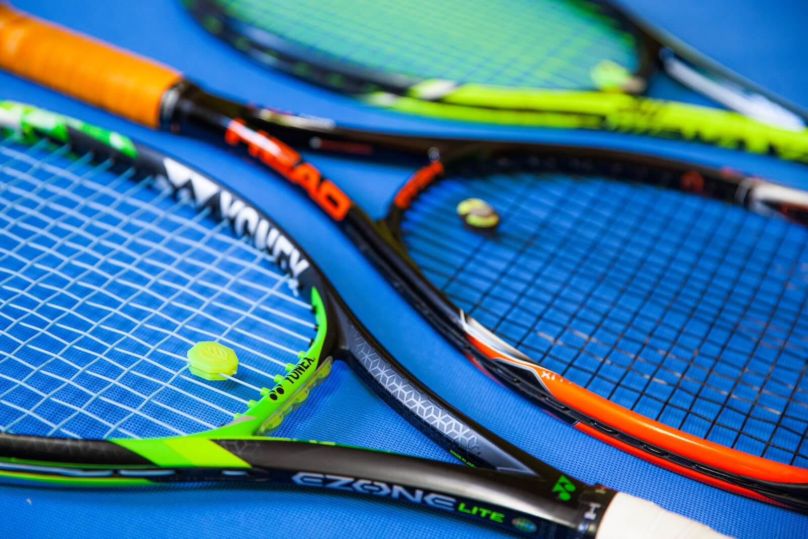 green and black tennis racket with others on ground