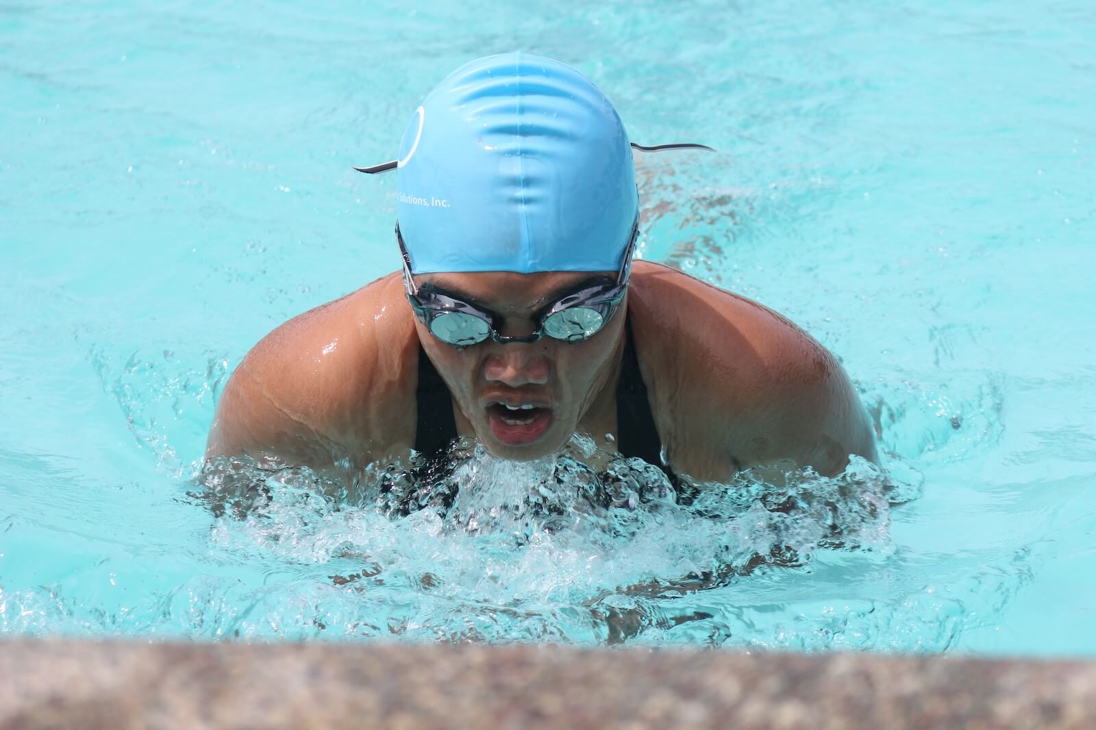 A woman swimming with goggles and a swim cap