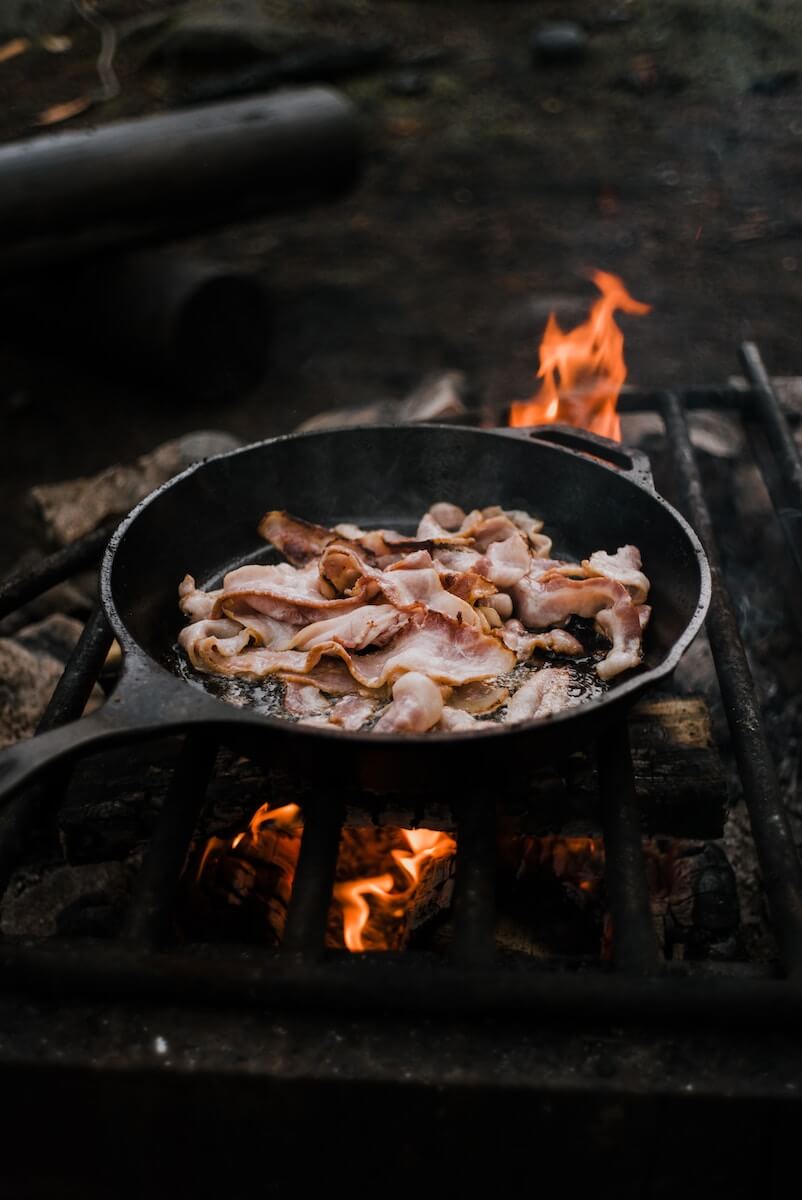 Bacon cooking over a grill's flame