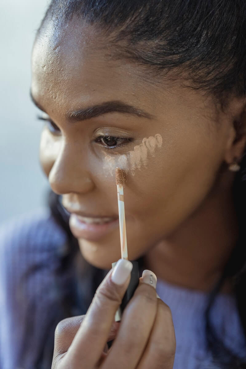A woman using concealer under her eyes