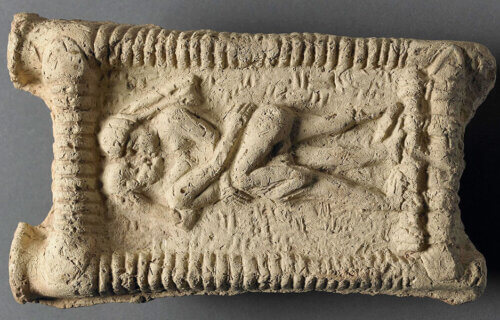Babylonian clay model showing a nude couple on a couch engaged in sex and kissing.