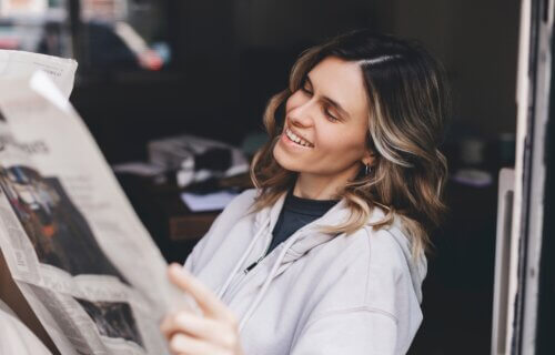 Woman smiles while reading newspaper