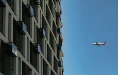 An airplane flies by an apartment building