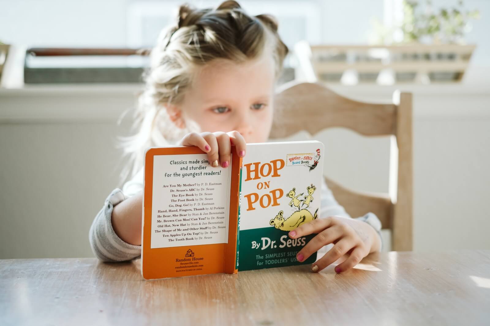 A little girl reading "Hop on Pop" by Dr. Seuss