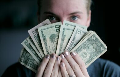 Person hides face with cash