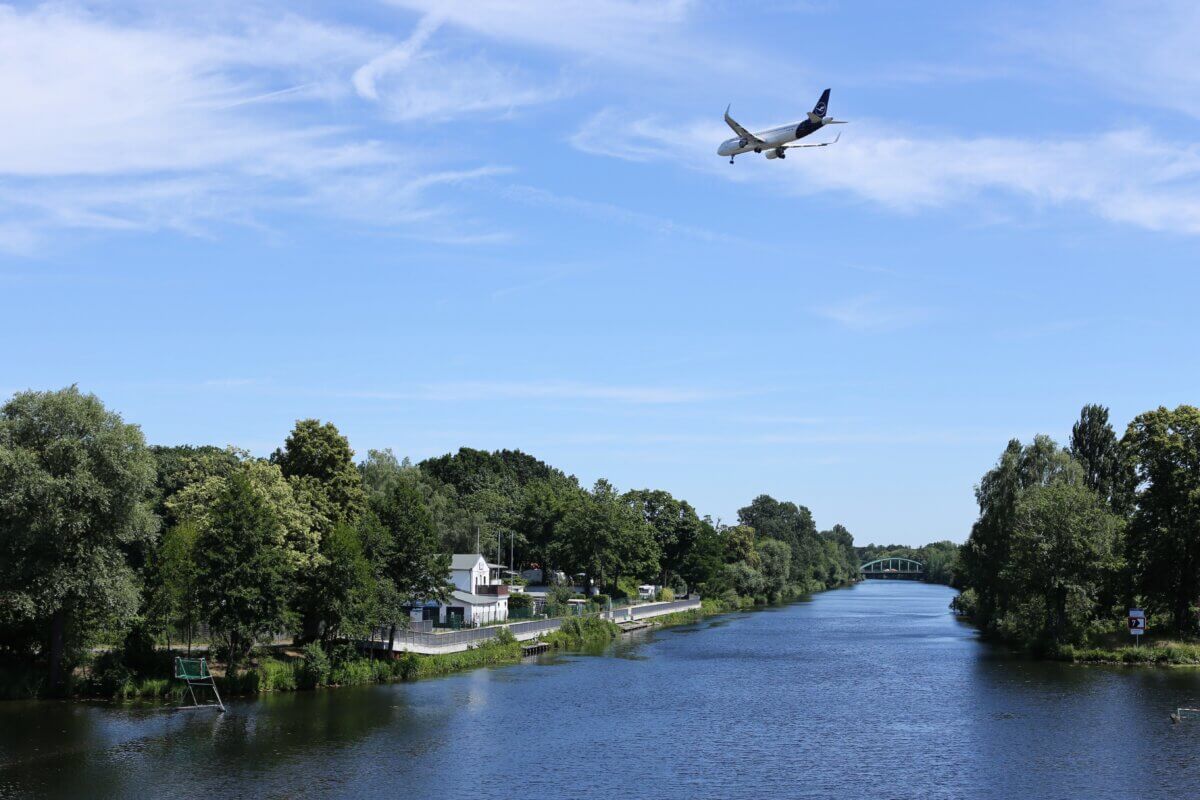 Airplane flying over a building and body of water