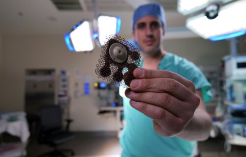 Doctor holds a skull-implantable ultrasound device to open the blood-brain barrier and repeatedly permeate large, critical regions of the human brain to deliver chemotherapy.